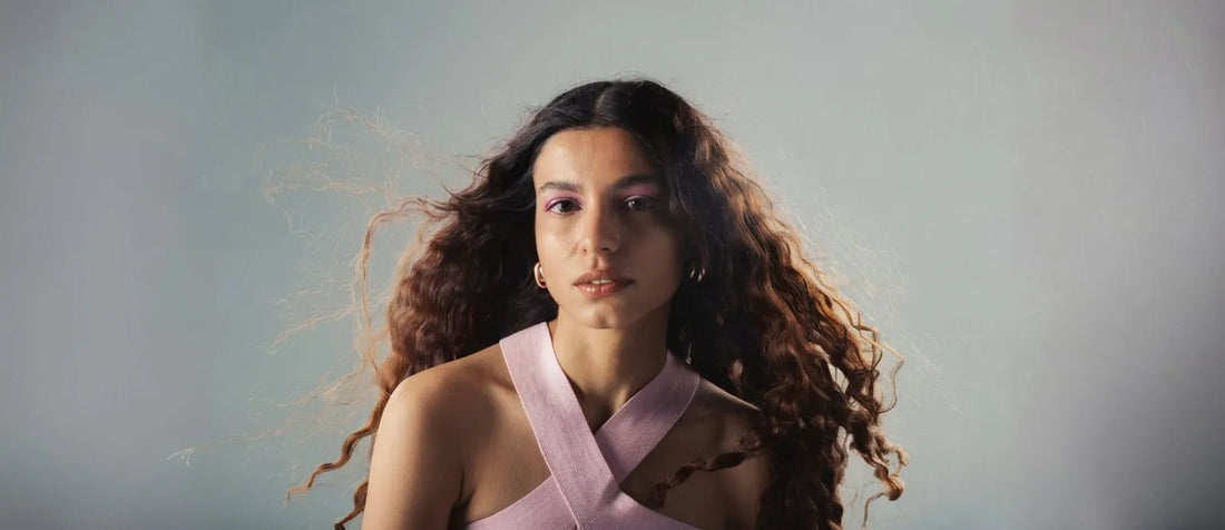 A woman demonstrating the plopping technique for enhancing natural curls in her hair.