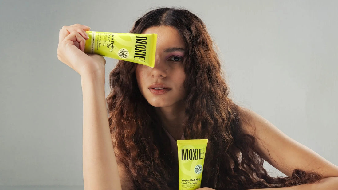 A woman with curly hair applying anti-frizz serum to reduce frizz and enhance shine.
