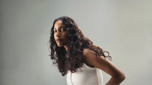A woman with naturally shiny hair enjoying the sunlight, showcasing healthy, vibrant locks and a radiant smile.